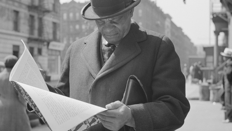 New York, New York. A. Marcus Garveyite reading the OWI (Office of War Information) publication Negroes and the War, April 1943. Library of Congress Prints and Photographs Division, Washington, D.C. 20540, USA. OWI was the Executive Branch agency under the control of the White House. Its Overseas Division produced World War II shortwave radio broadcasts, which were later named the Voice of America (VOA).